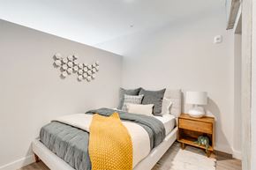 Saint Paul apartment for rent - A bedroom with a bed, pillows, a blanket, a nightstand, and a wall decoration.
