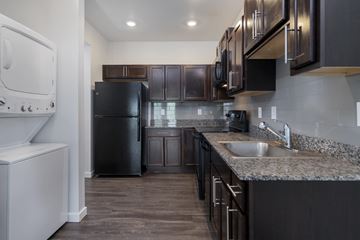 Lansing apartment for rent - A kitchen with a black refrigerator and brown cabinets.