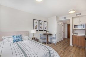 Battle Creek apartment for rent - A bedroom with a large bed and a small kitchenette.