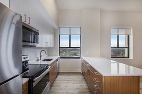 Battle Creek apartment for rent - A kitchen with a stainless steel refrigerator and a window overlooking a cityscape.