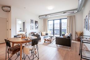 Pittsburgh apartment for rent - A living room with a brown sofa, a wooden table, and a black chair.