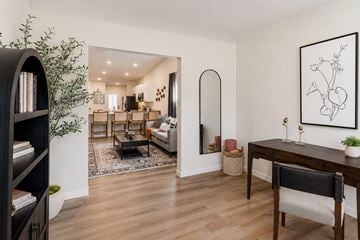 Kansas City townhouse for rent - A living room with a black bookcase, a coffee table, a couch, a chair, and a painting on the wall.