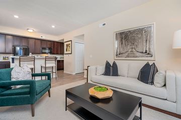 Lockbourne apartment for rent - A living room with a green chair, a black coffee table, and a white couch with a pillow.