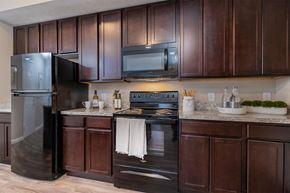 Lockbourne apartment for rent - A kitchen with dark brown cabinets and a black refrigerator.