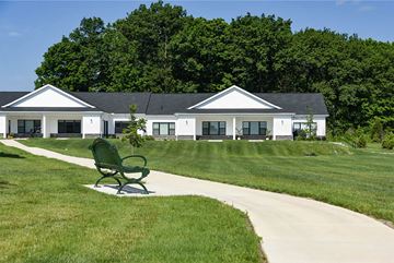 Oak Creek apartment for rent - A green bench is in the foreground of a white building with a black roof.