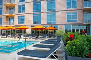 Cleveland apartment for rent - A pool area with sun loungers and umbrellas in front of a building.