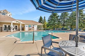 Orion Charter Twp apartment for rent - A pool area with a table and chairs under a blue and white striped umbrella.