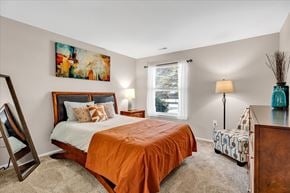 Orion Charter Twp apartment for rent - A bedroom with a large bed and a painting on the wall.