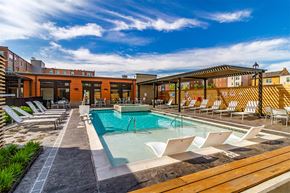 Detroit apartment for rent - A pool area with sun loungers and a building in the background.