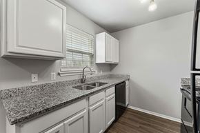 Rogers apartment for rent - A kitchen with granite countertops and white cabinets.