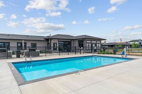 Albertville apartment for rent - A swimming pool in front of a building with a person standing by the pool.