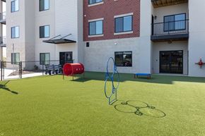 Rogers apartment for rent - A playground with a red and blue swing set and a green lawn.