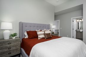 Cincinnati apartment for rent - A bedroom with a large bed and a grey headboard.