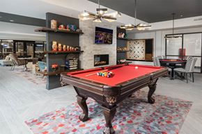 Cincinnati apartment for rent - A pool table is in the middle of a room with a fireplace and shelves with various items.