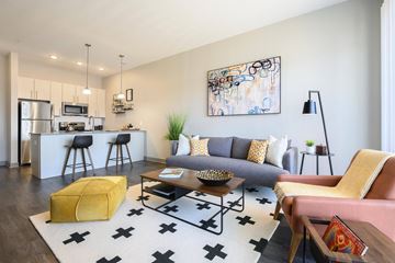 Covington apartment for rent - A modern living room with a yellow ottoman and a large abstract painting on the wall.