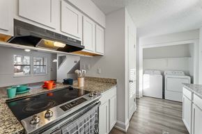 Bentonville apartment for rent - A kitchen with a black stove top oven and white cabinets.