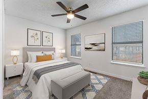 Bentonville apartment for rent - A bedroom with a bed, nightstands, and a ceiling fan.