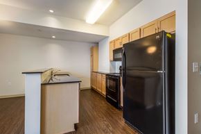 Detroit apartment for rent - A kitchen with a black refrigerator and wooden cabinets.