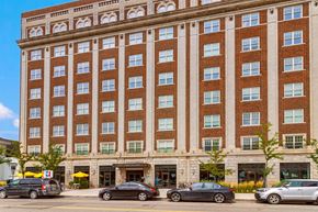 Detroit apartment for rent - A large red brick building with a parking lot in front.