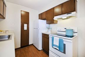 Farmington Hills apartment for rent - A kitchen with a white refrigerator, white stove, and wooden cabinets.