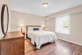 Farmington Hills apartment for rent - A bedroom with a bed, nightstand, and a round mirror on the wall.