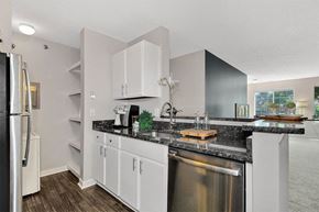 Troy apartment for rent - A kitchen with white cabinets and a black countertop.