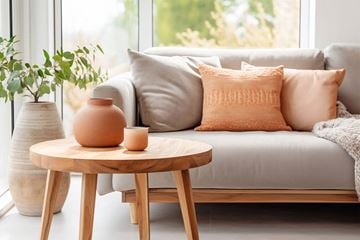 Little Rock apartment for rent - A living room with a grey couch, a round wooden table with a vase and candle on it, and a potted plant.