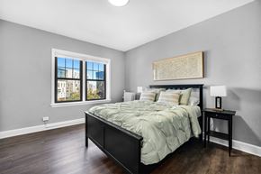 Cleveland apartment for rent - A bedroom with a large bed and a window overlooking a cityscape.