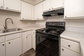 Little Rock apartment for rent - A black stove in a kitchen with white cabinets.