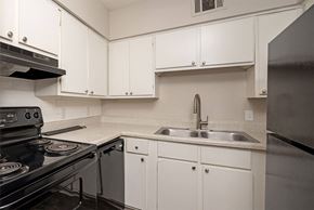 Little Rock apartment for rent - A kitchen with white cabinets and a black stove top.
