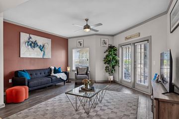 San Antonio apartment for rent - A living room with a grey sofa, a glass coffee table, a TV, and a painting on the wall.