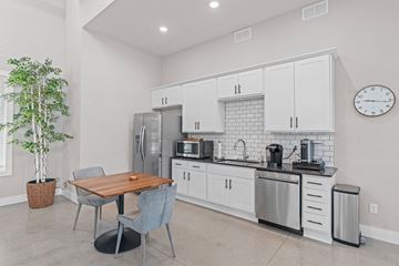 Victoria apartment for rent - A kitchen with a table and chairs in the foreground and a refrigerator, microwave, and oven in the background.