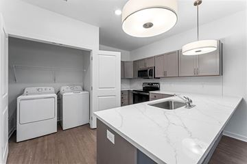 Rogers apartment for rent - A white kitchen with a marble counter top and a sink.