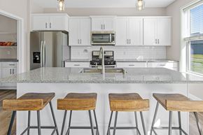 Woodbury apartment for rent - a kitchen with white cabinets and a white island with three wooden stools