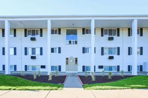 Kalamazoo apartment for rent - a white apartment building with a sidewalk and grass