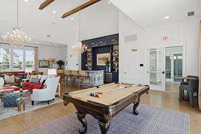 Perrysburg apartment for rent - A pool table in a room with a red couch and a chandelier.