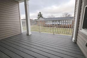 Cincinnati apartment for rent - A wooden deck with a white railing and a view of a building in the distance.