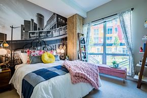 Detroit apartment for rent - A bedroom with a bed, a window with a view of a city, and a pink blanket.