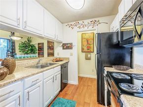 Morrisville apartment for rent - A kitchen with white cabinets and a black fridge.
