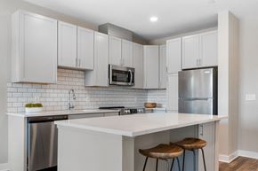 Cleveland apartment for rent - a kitchen with white cabinets and a white island with two stools