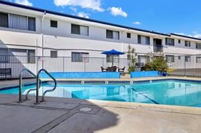 Tustin apartment for rent - A swimming pool in front of a building with a flag on it.