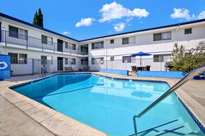 Tustin apartment for rent - A swimming pool in front of a building with a blue sky in the background.