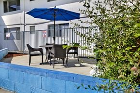 Tustin apartment for rent - A blue umbrella is on a table outside a building.