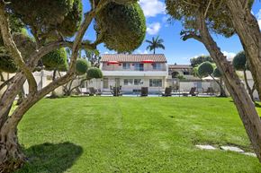 Fullerton apartment for rent - A house with a red roof is surrounded by a green lawn and trees.