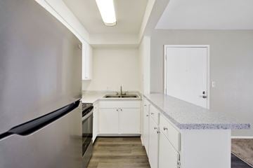 Redlands apartment for rent - A kitchen with a refrigerator on the left and a sink with a countertop on the right.
