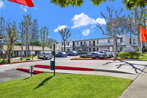 Brea apartment for rent - A sunny day at the Heritage Apartments with cars parked and trees in the background.