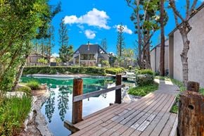 Santa Ana apartment for rent - A wooden walkway leads to a serene pond in a sunny garden.
