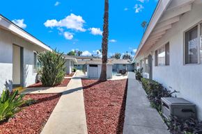 Redlands apartment for rent - A white building with a red mulch pathway in front.
