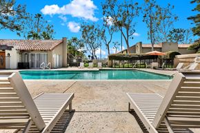 Fountain Valley apartment for rent - Two sun loungers sit on a poolside in front of a house.