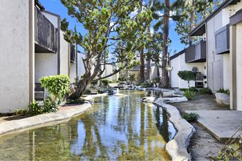A small canal with a waterfall in the middle of a residential area.